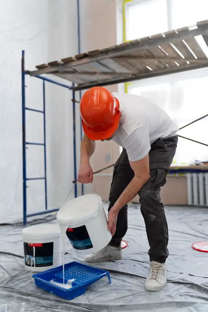 Trabajador preparando pintura blanca en bandeja para pintar interior de vivienda